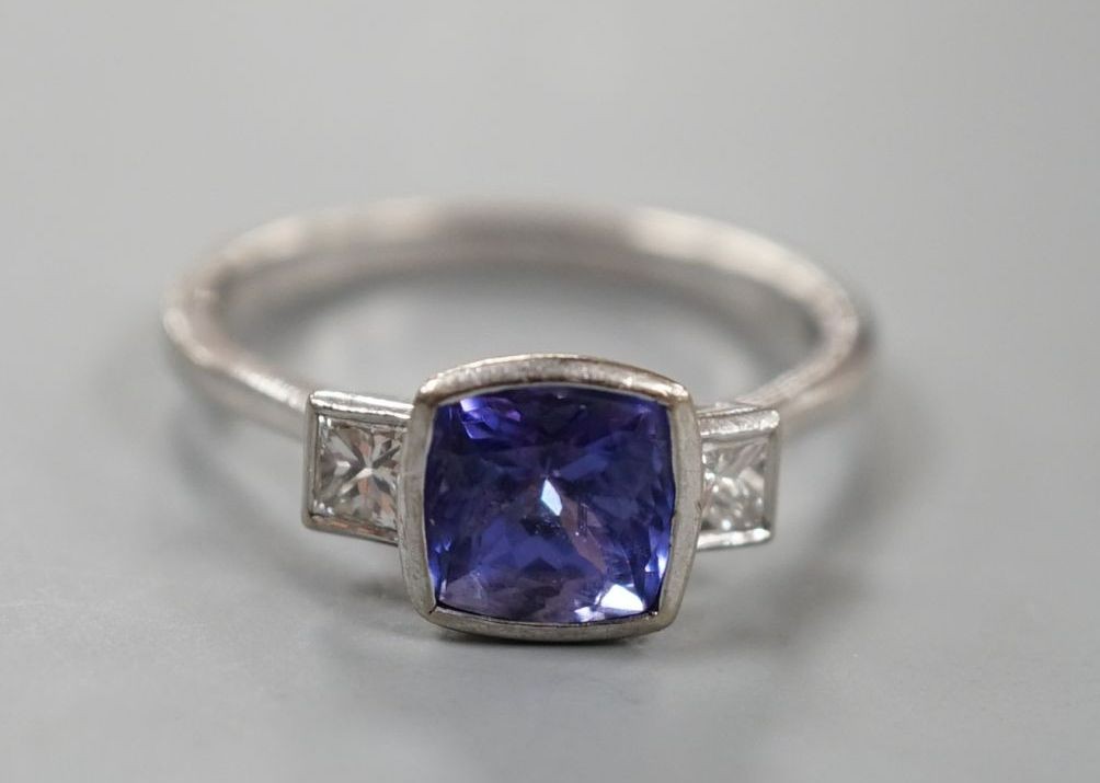 A modern 18ct white gold, single stone tanzanite and two stone diamond set ring, size R, gross weight 5 grams.